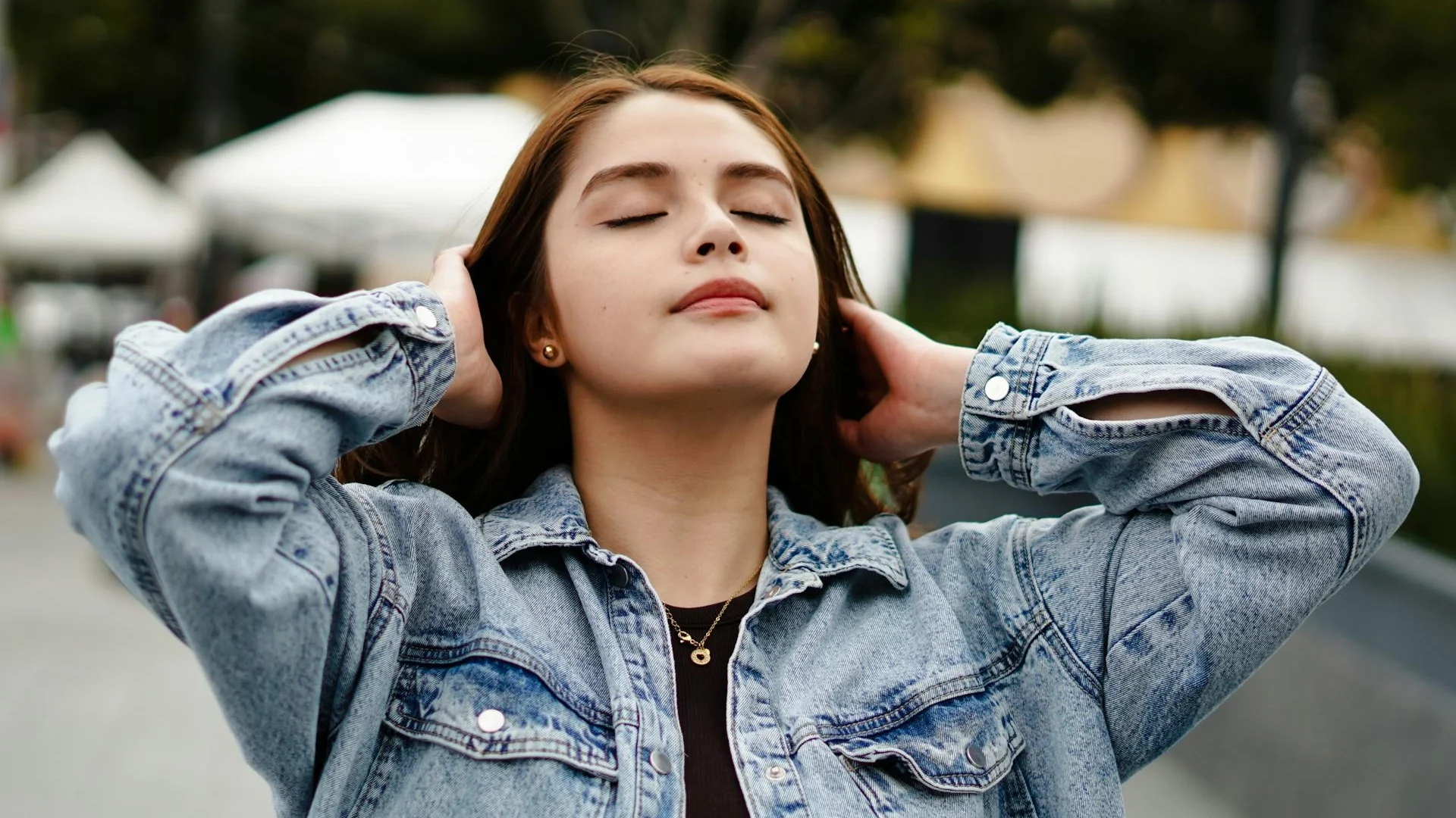 Young woman with eyes closed enjoying a serene moment outdoors