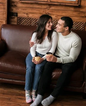 Couple sharing tea together on a cozy couch by a window